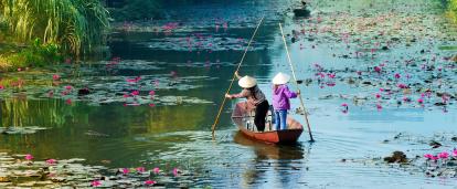Two locals travel across a lake in Vietnam. Locals kayak through the waters of Hanoi in Vietnam.